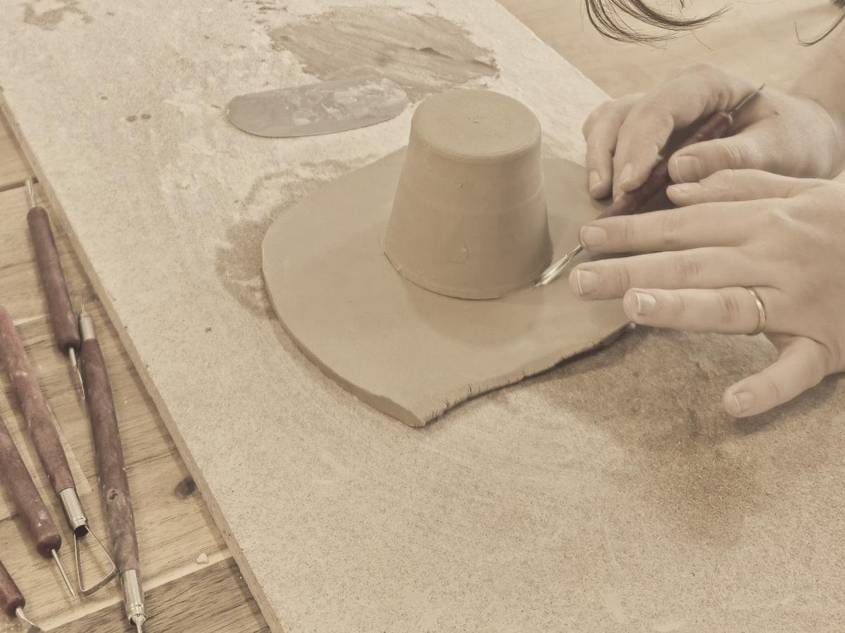 Mãos a esculpir um modelo de gesso sobre a bancada
